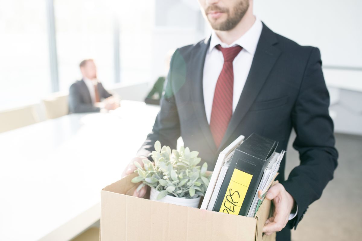 Businessman holding box of personal belongings after being laid off