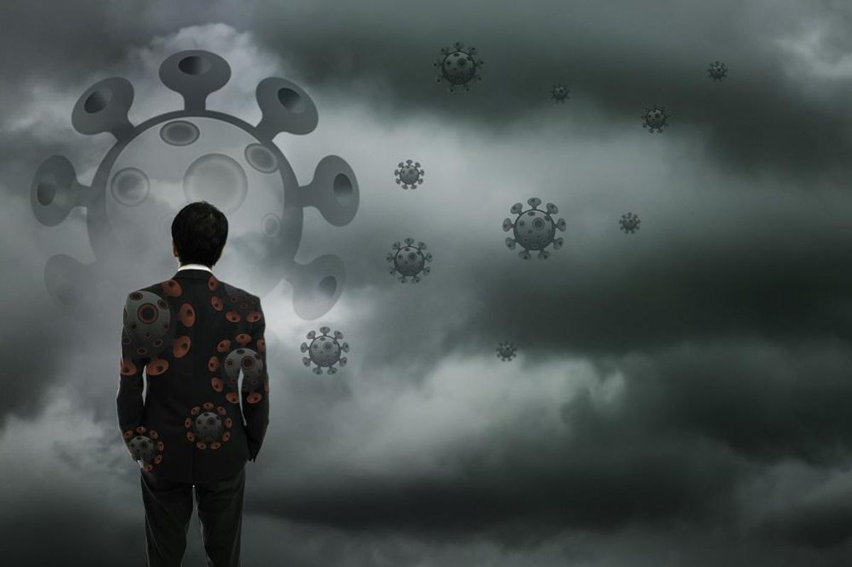 Businessman standing with corona virus cloud