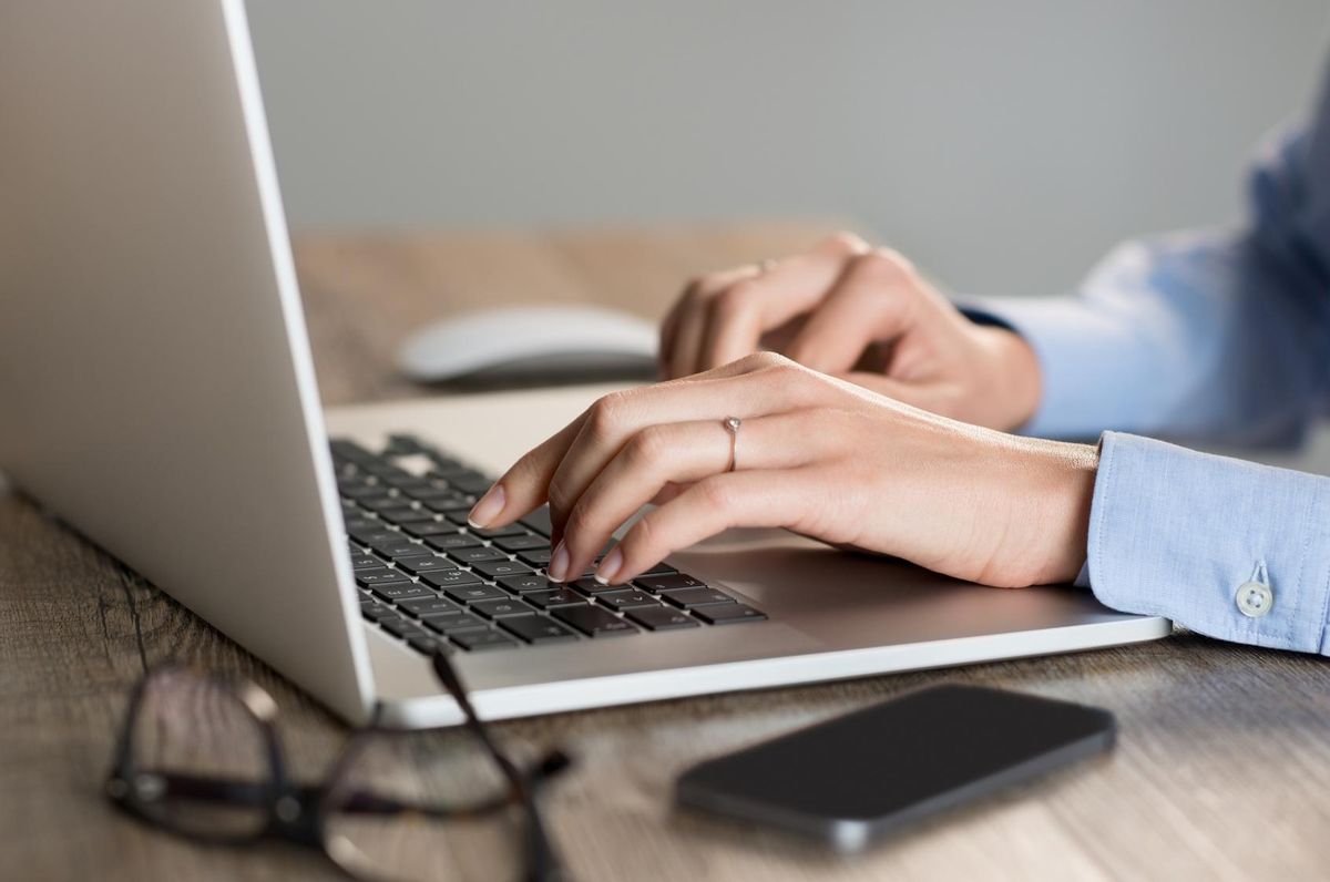 Closeup os a woman's hands typing on laptop
