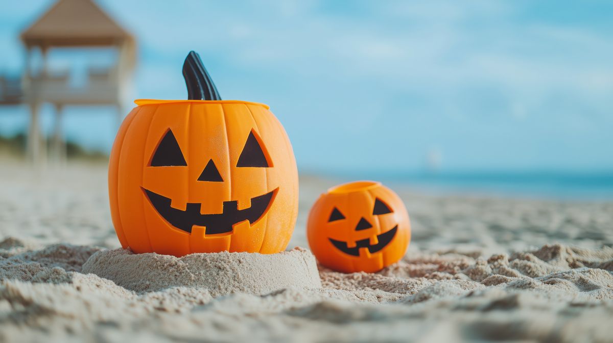Summerween jack-o'-lanterns on sandy beach under clear sky