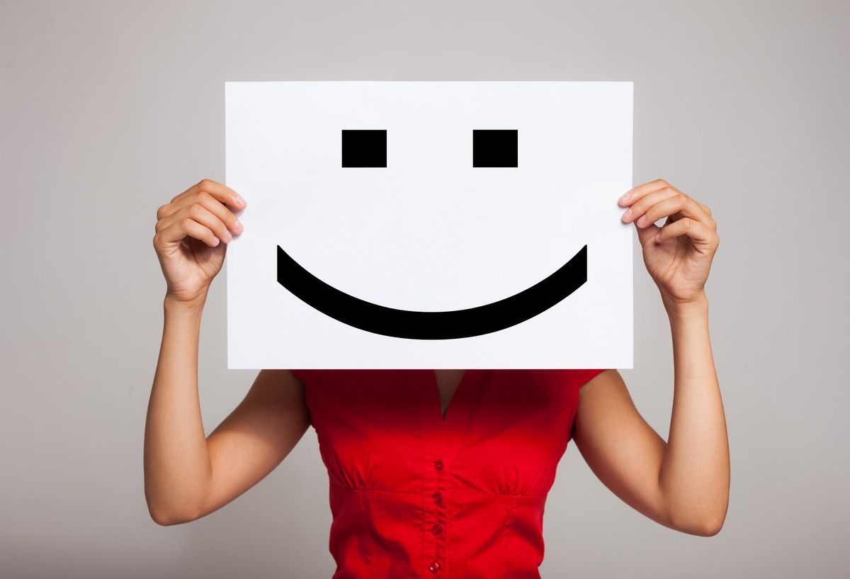 Woman holding a smiling face emoticon